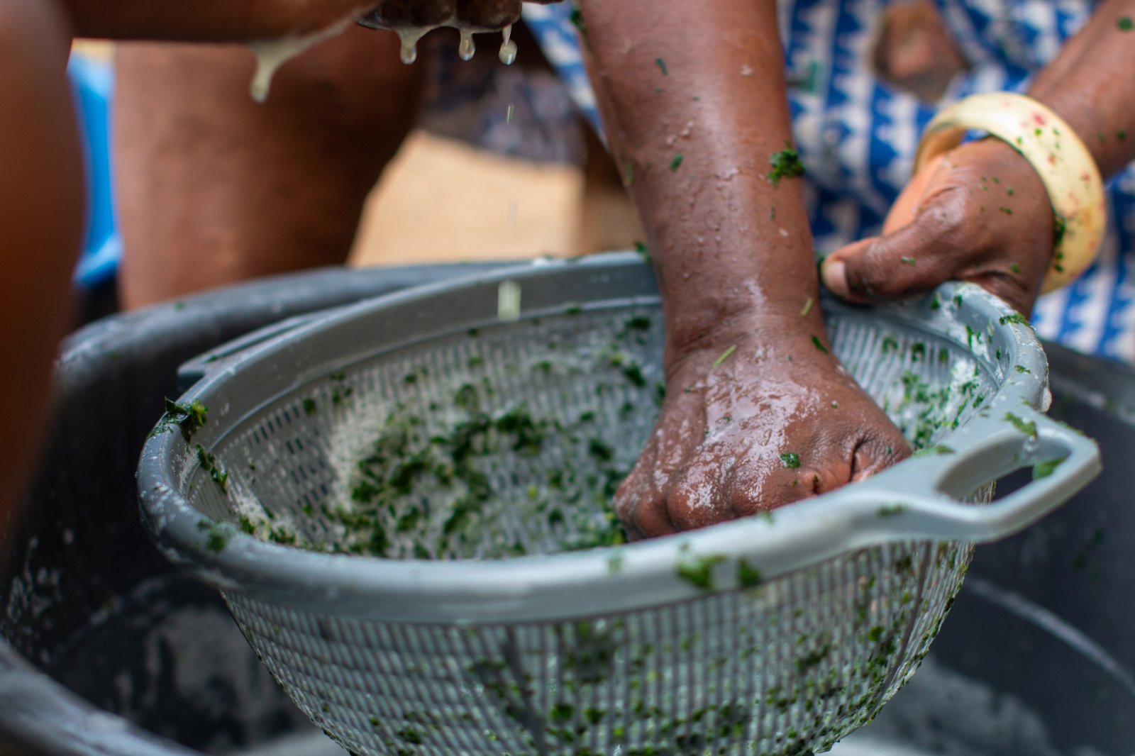 Hands washing fresh leafy ingredients in a colander